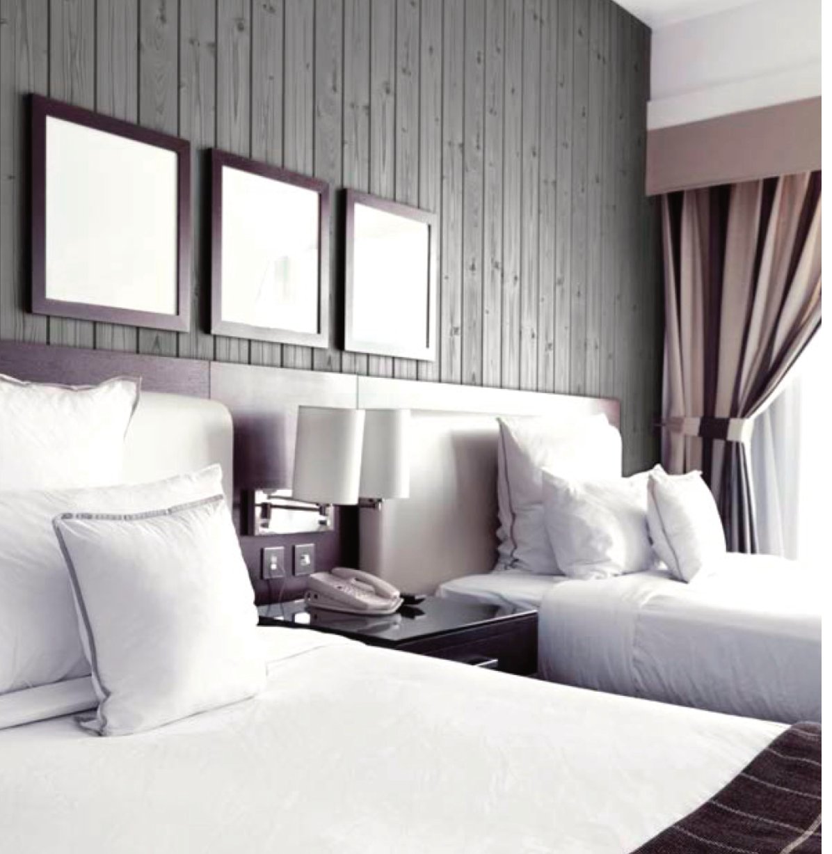Dormitorio de hotel con pared revestida en frisos color gris piedra acabado rústico seda